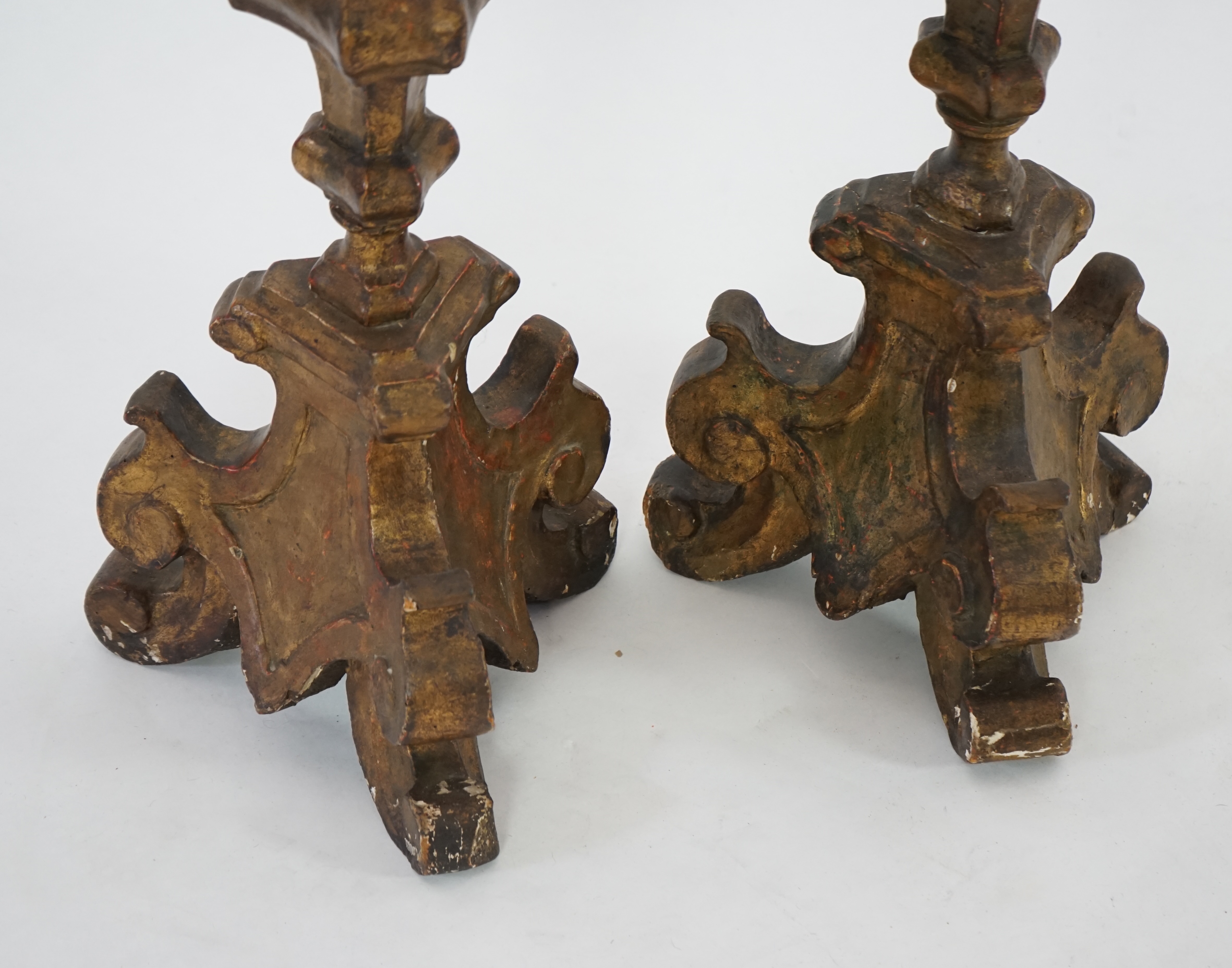 A pair of 18th century Italian giltwood candlesticks with knopped triangular stems and scroll feet, 89cm high. Condition - fair, Provenance- Brede Place, East Sussex, a former residence of the Frewen family from 1712-193
